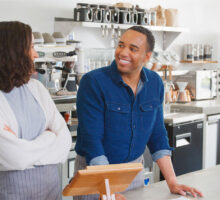 Man and a woman behind the counter of a coffee shop.