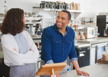 Man and a woman behind the counter of a coffee shop.