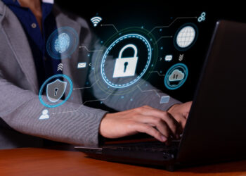 Cyber Liability concept with a man sitting at a laptop with security icon floating around.